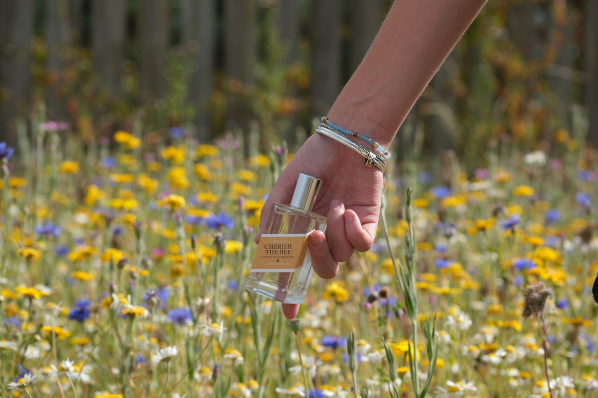 A bottle of Middleshade perfume held in the wildflower meadow at Tarhill Farm